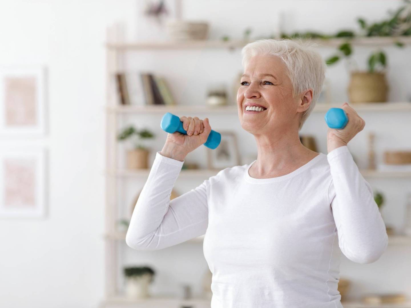 Senior woman exercising with blue dumbbells